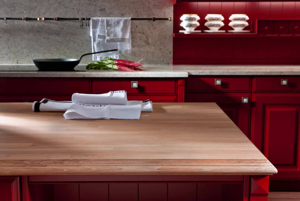 Rote Landhausküche in L-Form mit dunklem Fliesenboden. Foto: Leicht Küchen