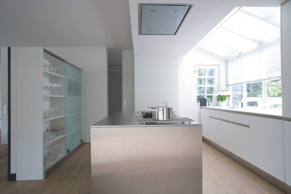 Weiße Küche mit Kochinsel und Arbeitsplatte aus Edelstahl; Foto: allmilmö