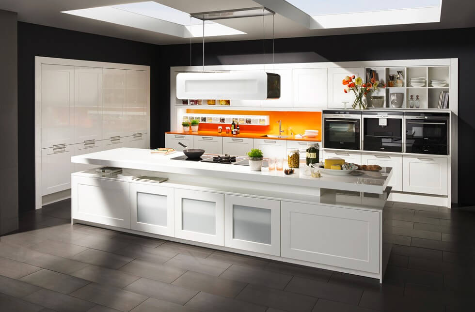 Weiße Küche mit Insel und orangem Spritzschutz; Foto: DAN Küchen