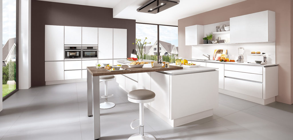 Grifflose Küche mit weißen Fronten, Griffleisten, Kochinsel und Theke mit Barhockern; Foto: Nobilia