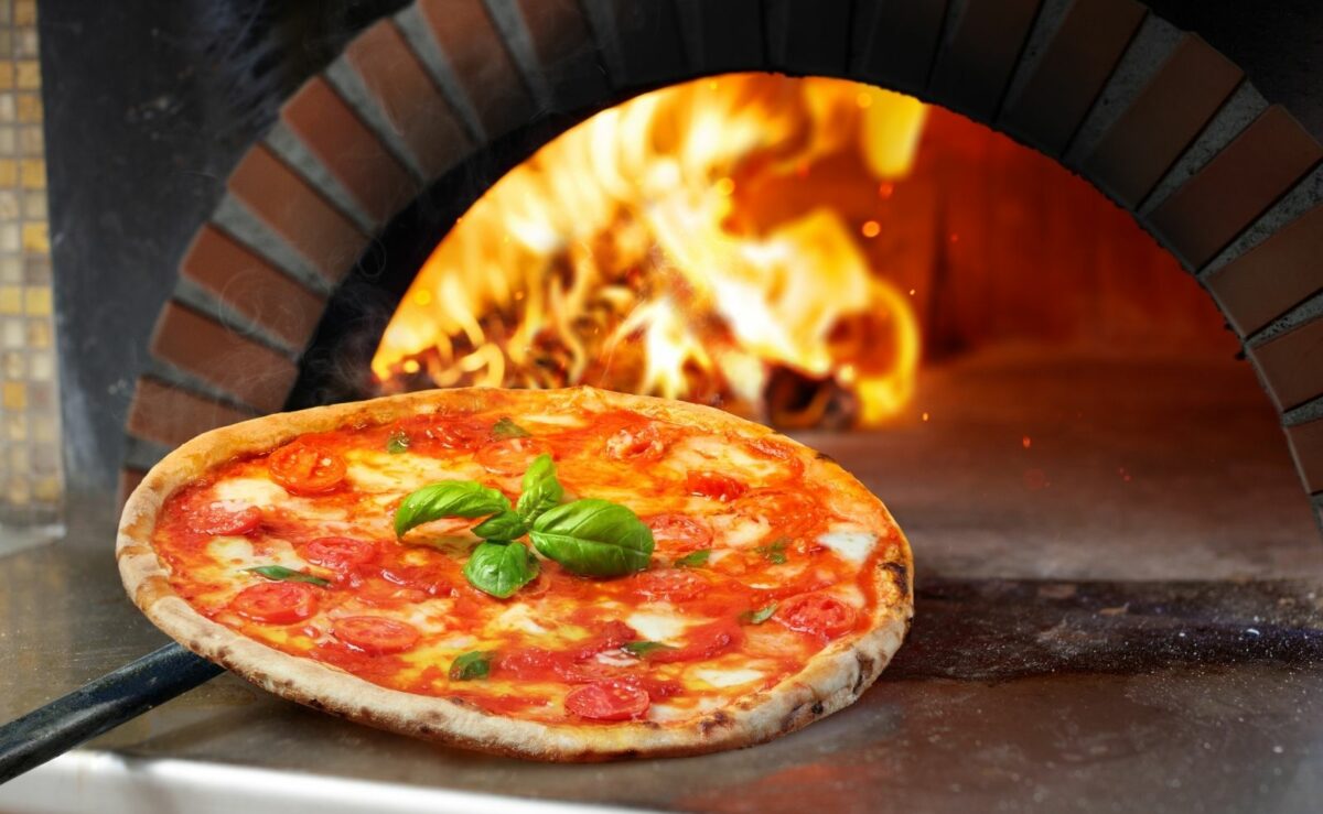 Profis backen die Pizza im Holzofen bei Temperaturen von 250 °C bis 300 °C