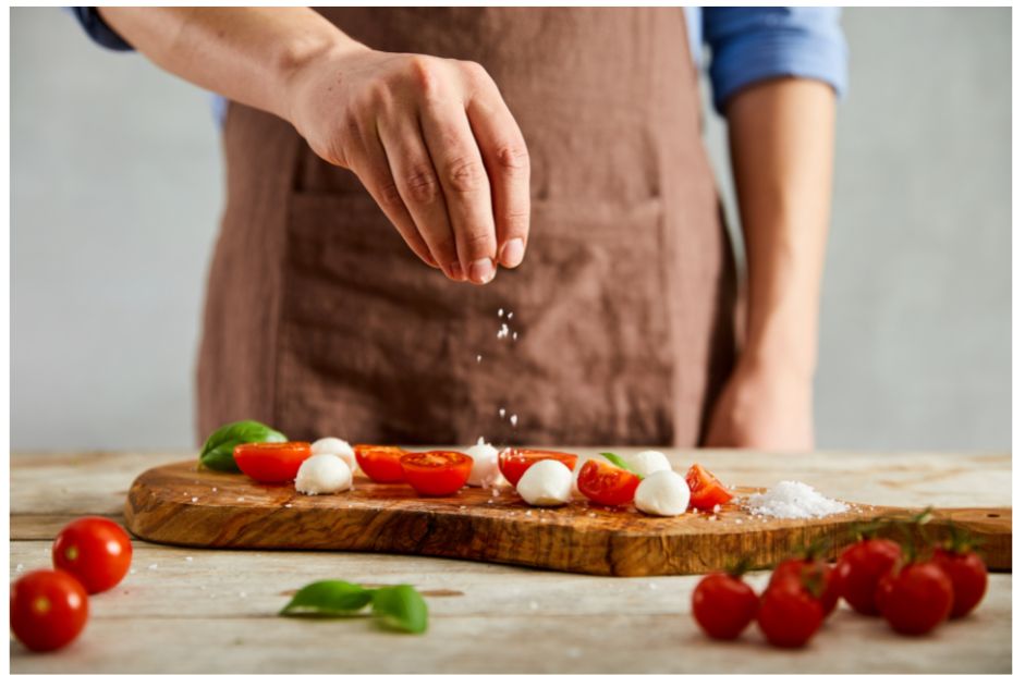 Eine Prise Salz wird auf Tomaten und Mozzarella gestreut