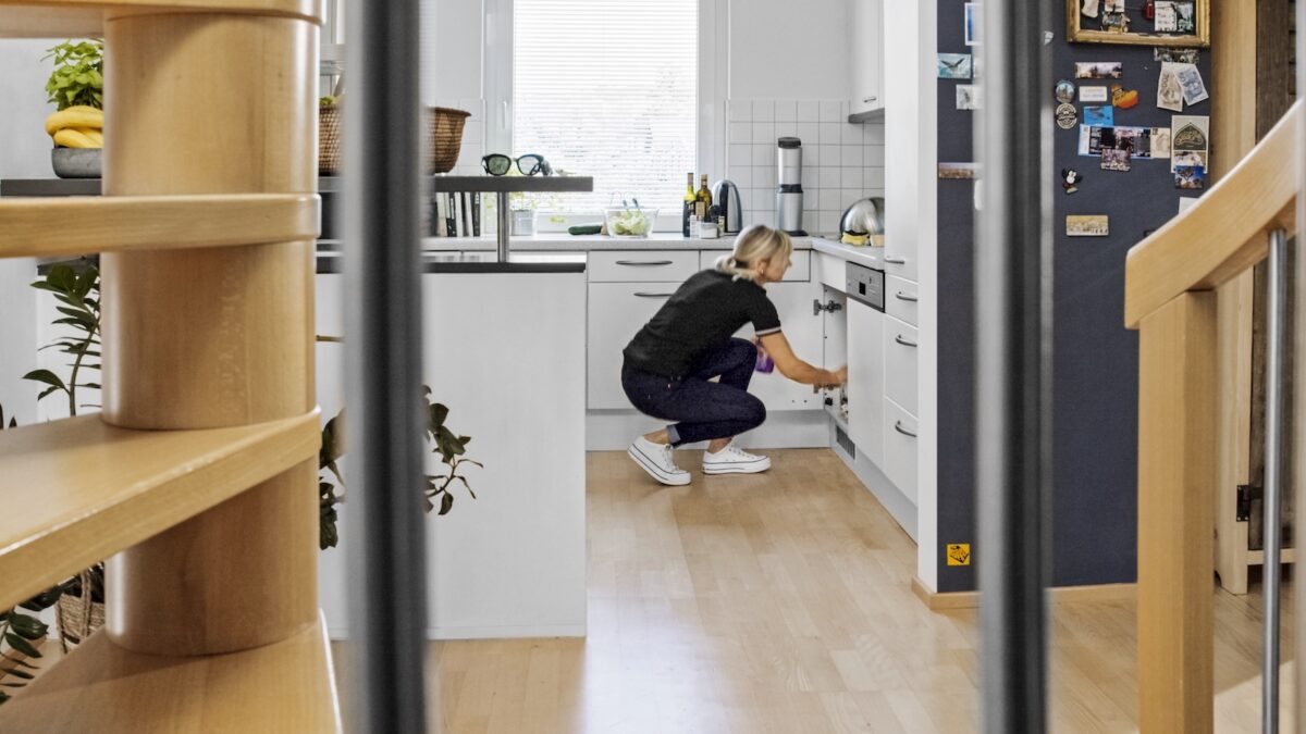 Frau bückt sich in einer Küche um die Unterschränke einzuräumen