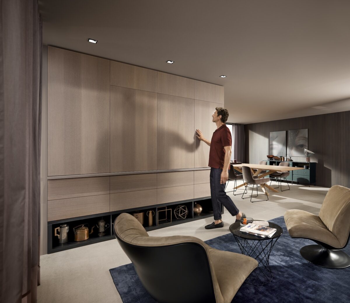 Ein Mann schließt den REVEGO-Aufsatzschrank; die Schrankfront ist bündig und minimalistisch gestaltet, keine Griffe sichtbar. Foto: Julius Blum GmbH