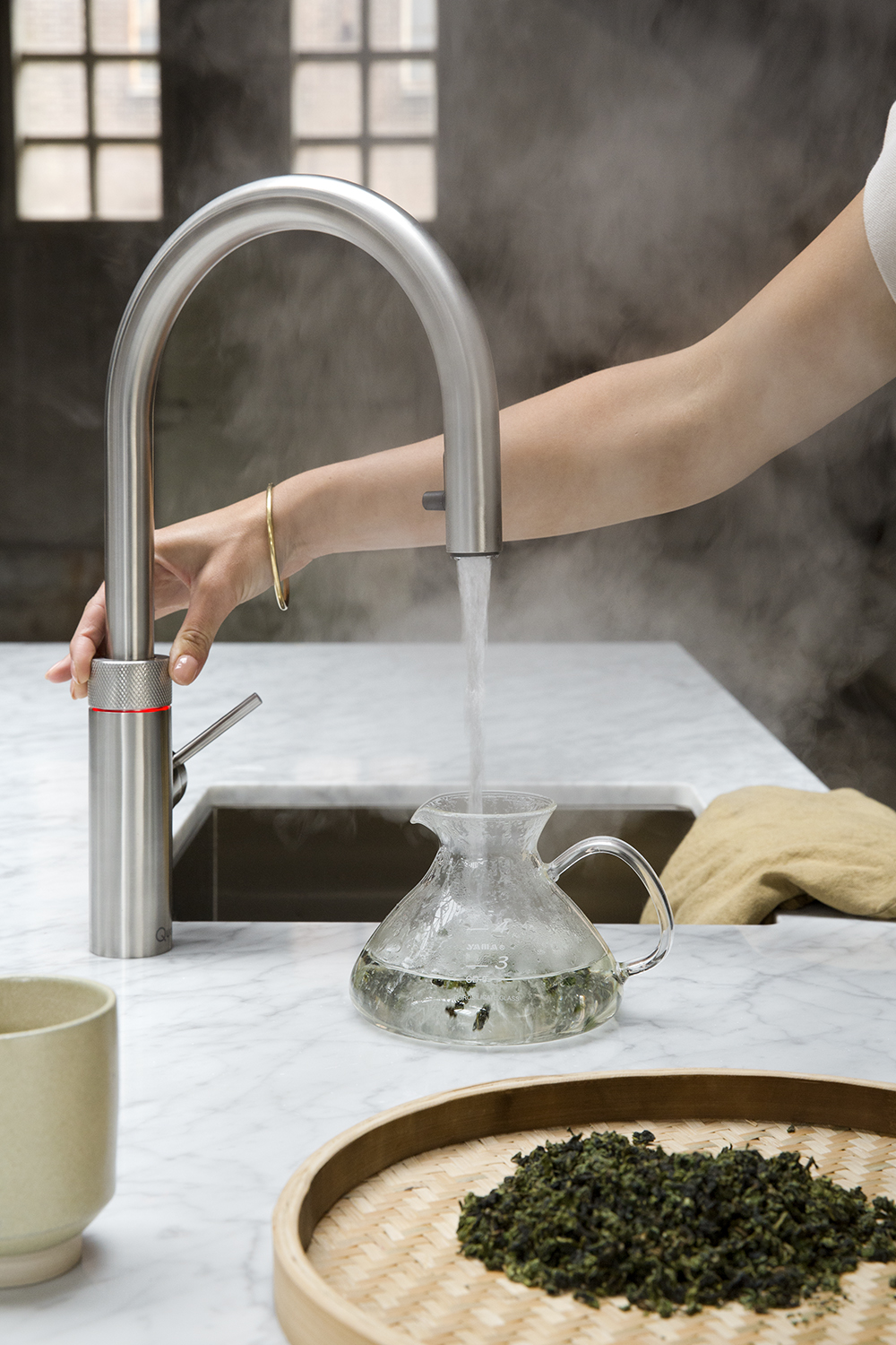 Moderne Küchenarmatur von Quooker gibt 100 °C heißes Wasser für Tee aus. Die Dampfsäule zeigt die hohe Temperatur.