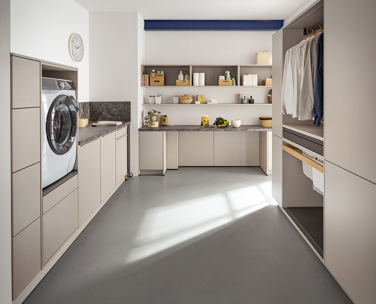 Heller Hauswirtschaftsraum mit Waschmaschine, Stauraum, Arbeitsflächen und offenen Regalen in modernem Design. Foto: AMK