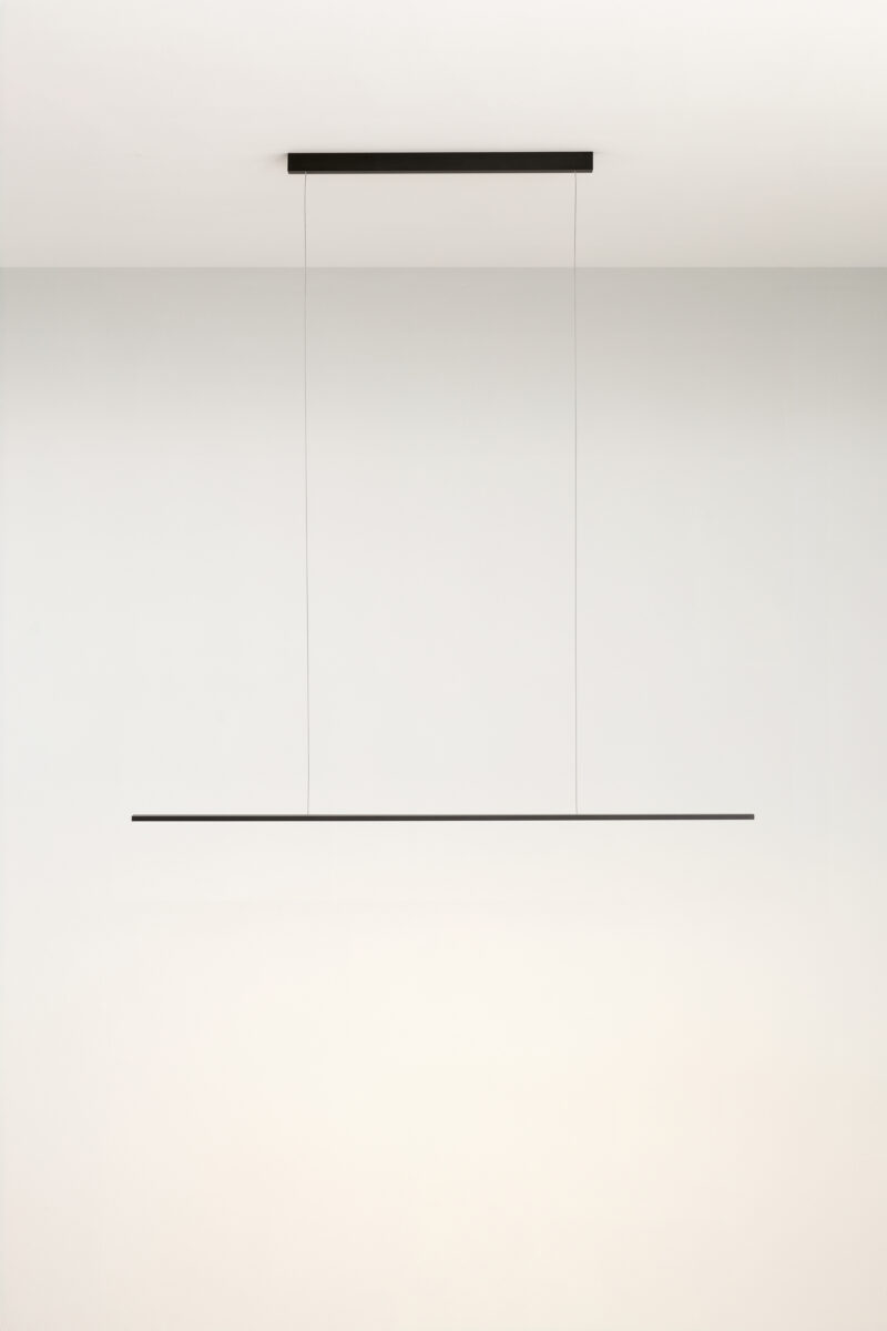 Schmale, horizontale Pendelleuchte vor weißer Wand, klare geometrische Optik