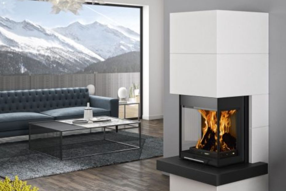 Offener Wohnbereich mit großen Fenstern, blauer Couch und weißer Verkleidung eines ORANIER Heizkamins; moderne Loft-Optik.