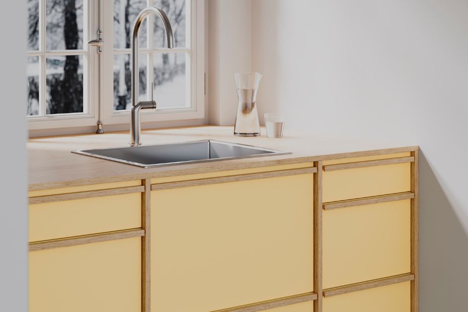 Küche mit wachsgelben, matten Fronten und natürlicher Holzstruktur unter einem großen Fenster