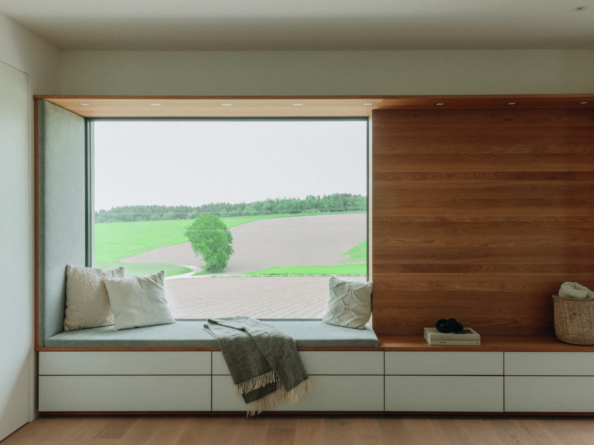 Große Fensterbank und Wandpaneel in geöltem Holz, modernes Tageslichtambiente mit Ausblick.