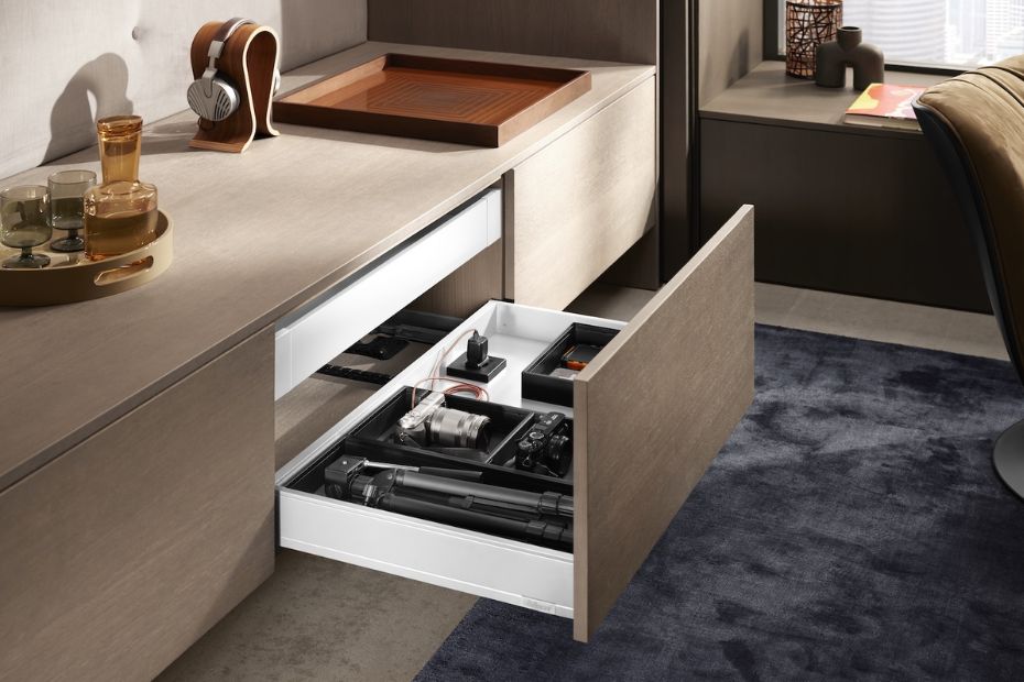 Geöffnete Schublade in einem Wohnmöbel, ausgestattet mit AMPEROS AC zur unsichtbaren Stromversorgung, in der Kameraausrüstung ordentlich verstaut und geladen wird.