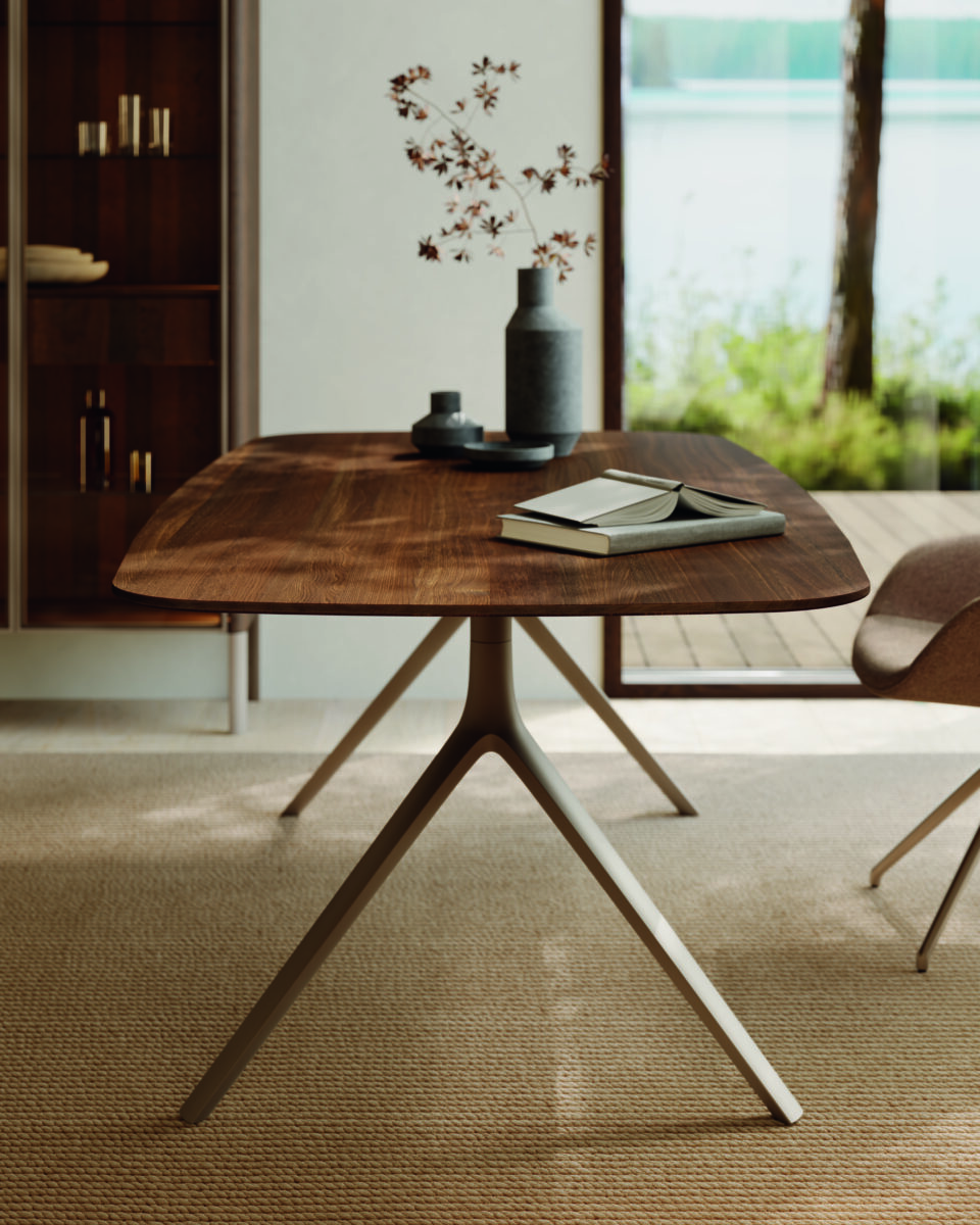 Runder Holztisch mit Keramikdeko in offenem, lichtdurchflutetem Wohnraum