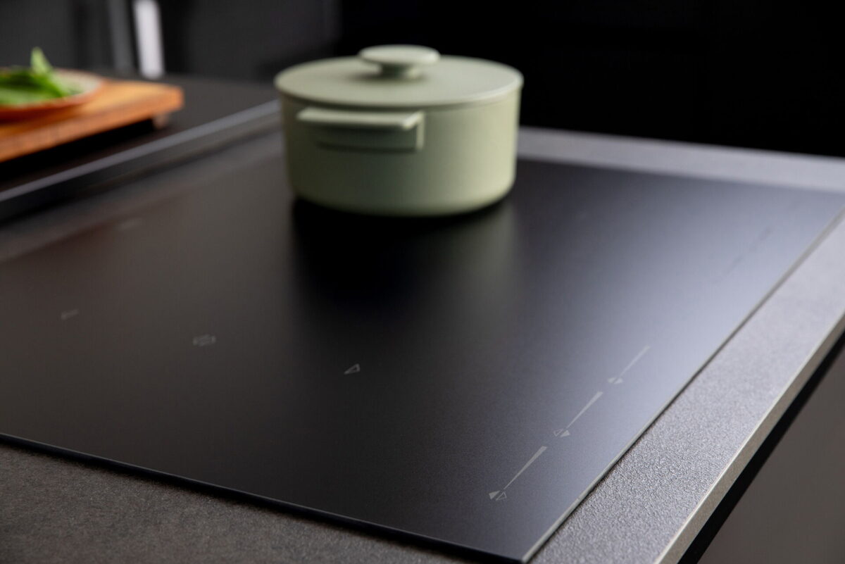 Schwarzes Induktionskochfeld mit Topf, flächenbündig in moderne Küchenarbeitsplatte integriert