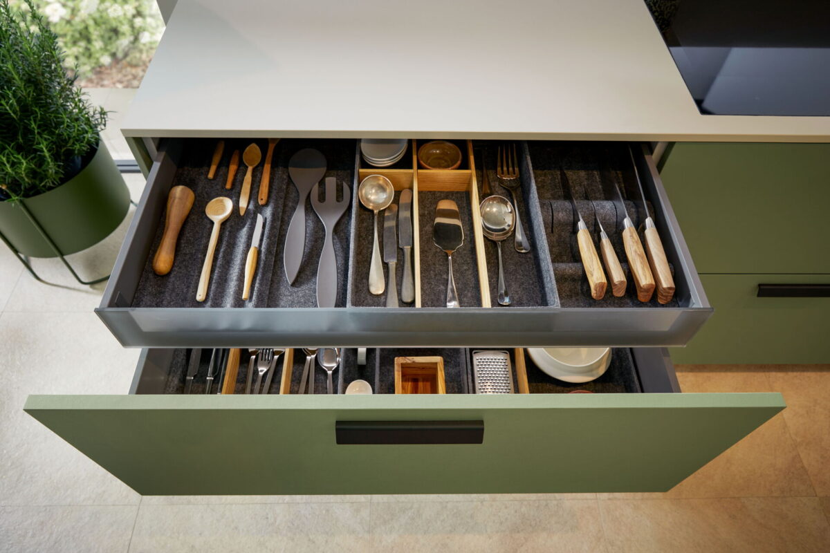 Küchenschublade mit hochwertigem Besteckeinsatz und strukturierter Innenorganisation aus Holz und Filz.