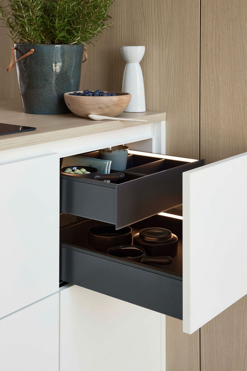 Moderner Küchenauszug mit zusätzlichem Innenschubkasten und integrierter Beleuchtung für mehr Stauraum und Übersicht.