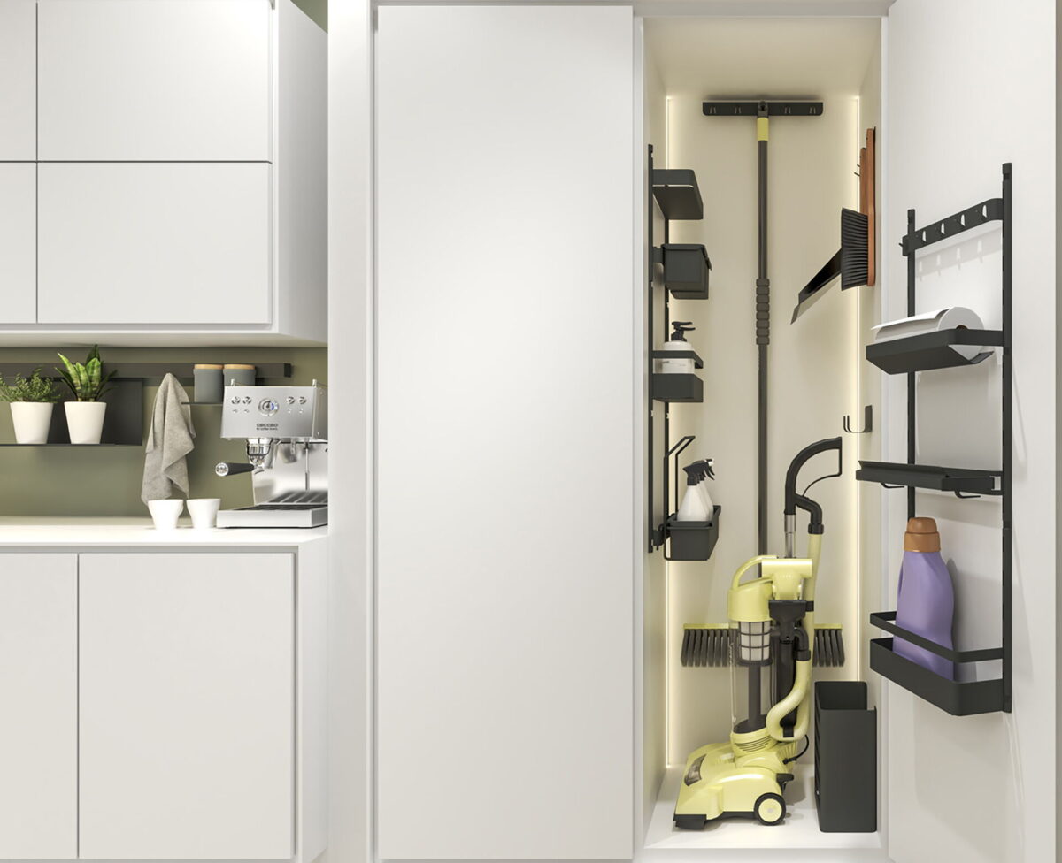 Schmaler Putzschrank in einer kleinen Küche mit integriertem Staubsauger, Ablagen und Wandhalterungen für Reinigungszubehör.