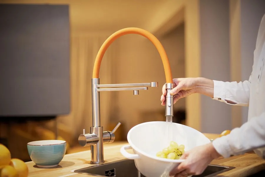 Edelstahl LivingTap Pro Küchenarmatur mit flexiblem orangefarbenem Schlauch beim Spülen von Obst in moderner Küche