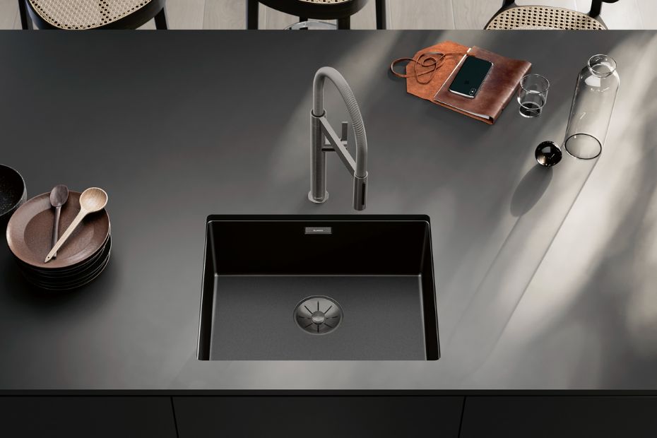 Moderne schwarze Einbauspüle mit Armatur auf dunkler Küchenarbeitsplatte