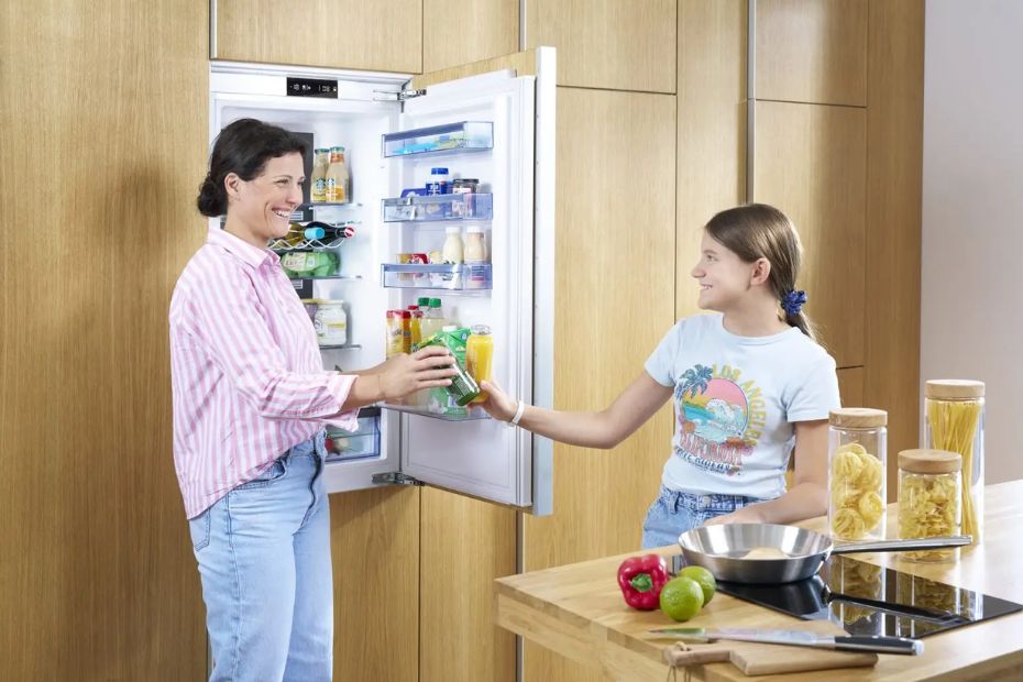 Mutter und Tochter stehen vor geöffnetem ORANIER Kühlschrank