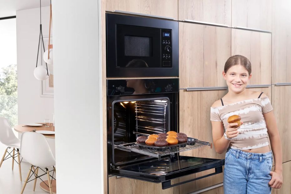 Kind steht vor geöffnetem ORANIER Backofen in moderner Familienküche