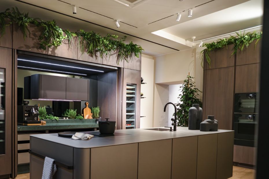 Moderne Wohnküche mit dunkler Kücheninsel, Holzfronten, Pflanzen und indirekter Beleuchtung auf der Milano Design Week 2026