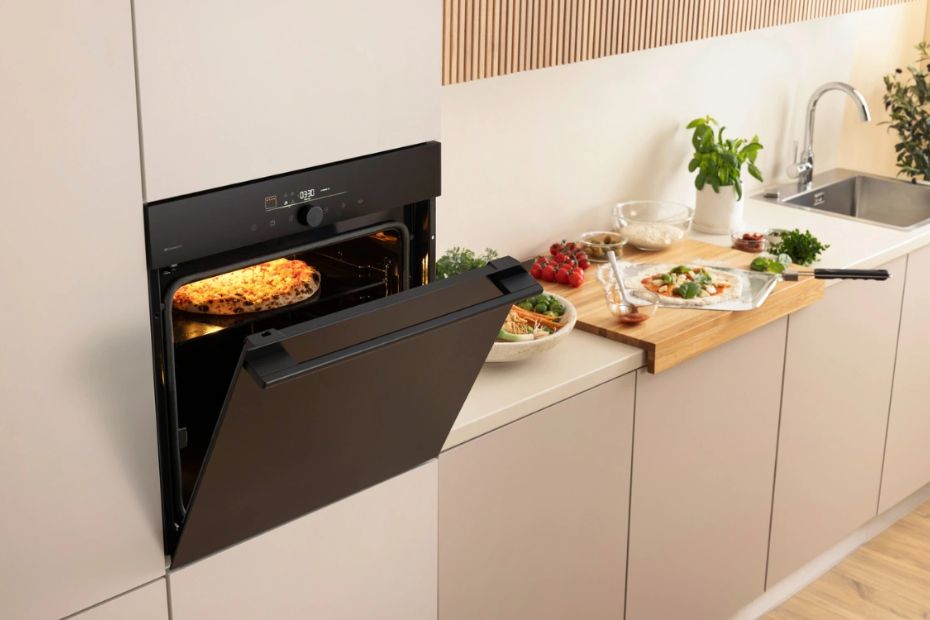 Moderner Gorenje Einbau-Backofen mit Pizza-Programm und geöffneter Backofentür in heller Wohnküche mit Pizza auf dem Backblech