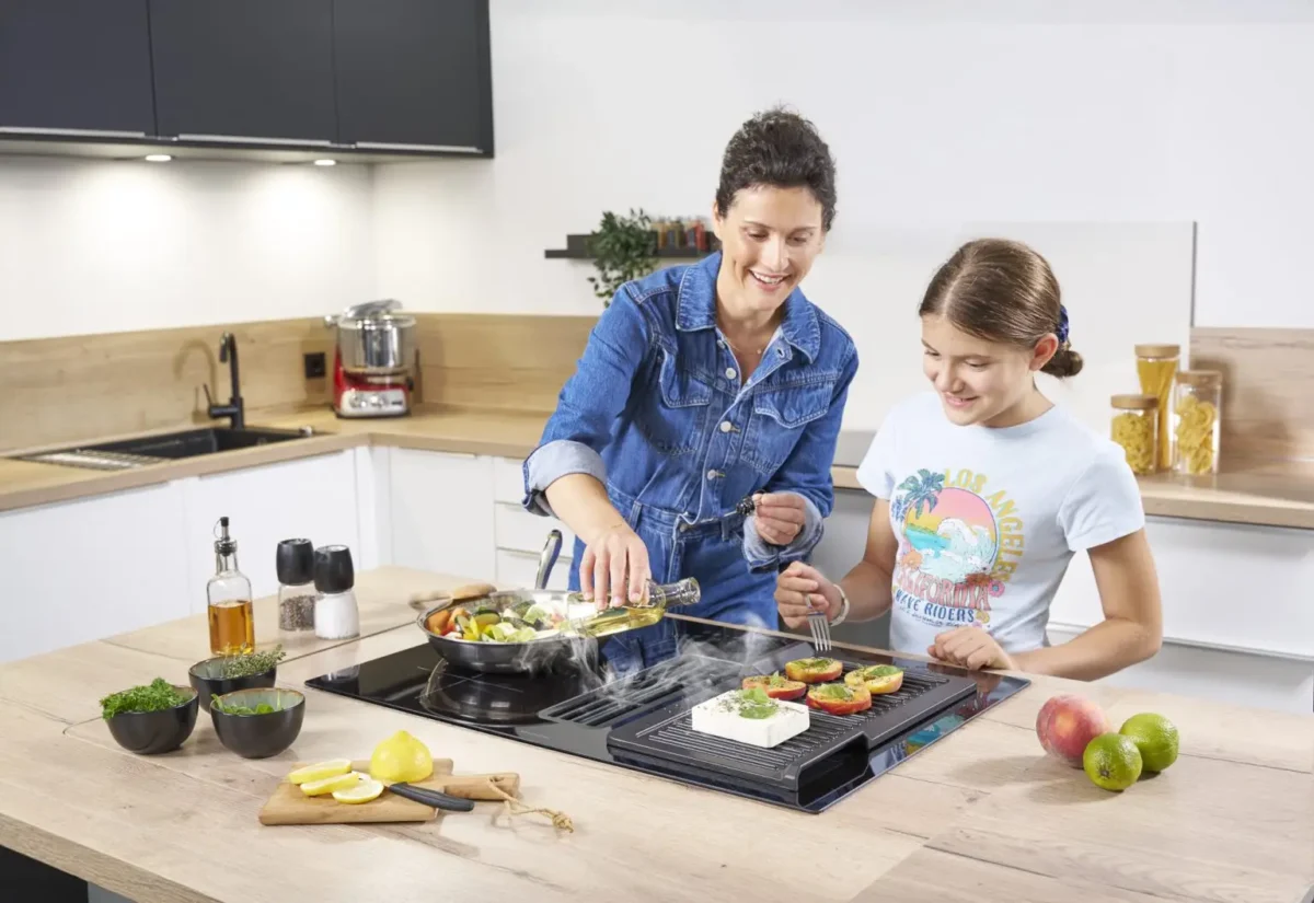 Mutter und Kind kochen gemeinsam an Kücheninsel mit ORANIER Kochfeldabzug