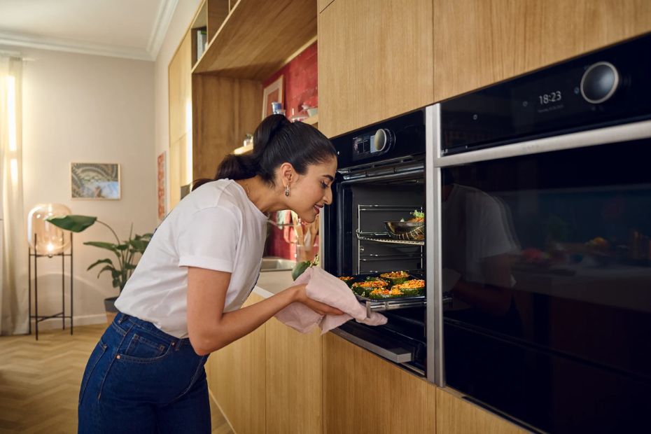 Person nimmt ein Blech aus einem Neff Backofen mit Slide & Hide Tür