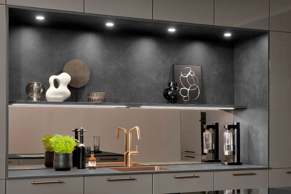Moderne Küche mit glatten Fronten, beleuchteter Nische, dunkler Rückwand und kupferfarbener Armatur