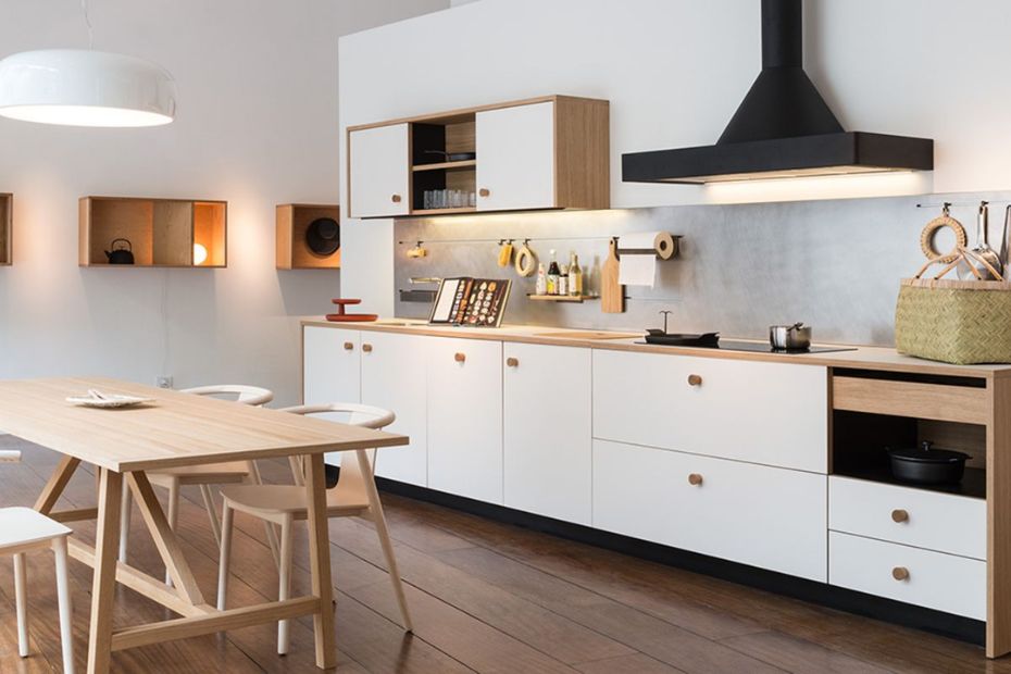 Helle Küche mit weißen matten Fronten, Holzdetails, schwarzer Dunstabzugshaube und Essbereich