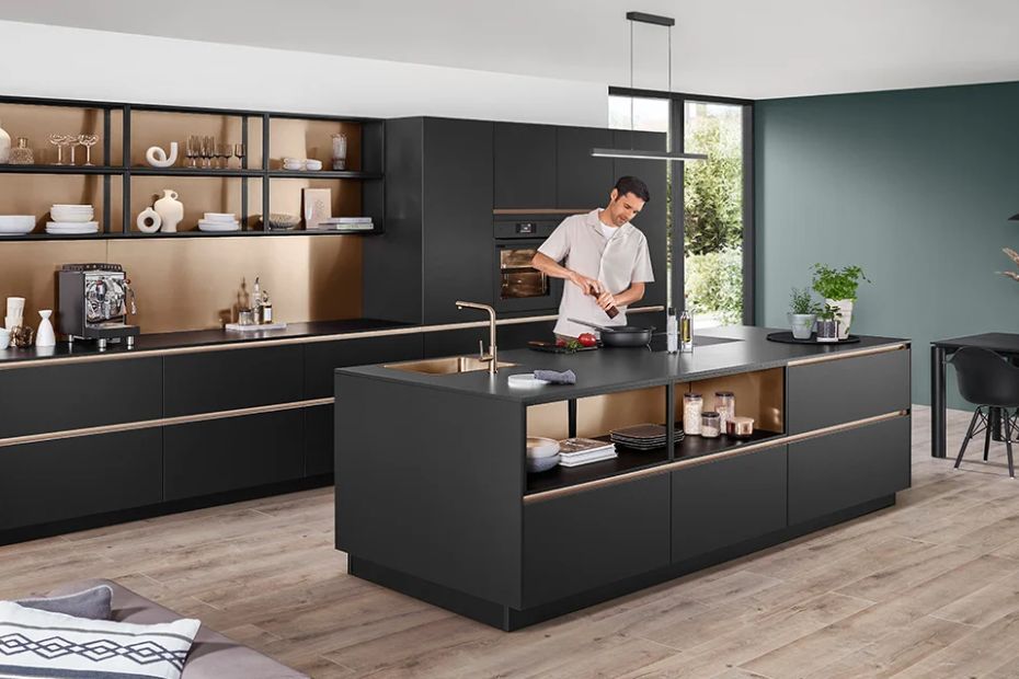 Moderne Küche mit dunklen matten Fronten, Kücheninsel, offenen Regalen und Person beim Kochen