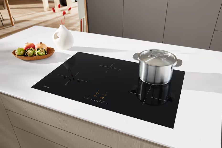 Miele Induktionskochfeld auf heller Kücheninsel mit Topf und schwarzer Glasfläche