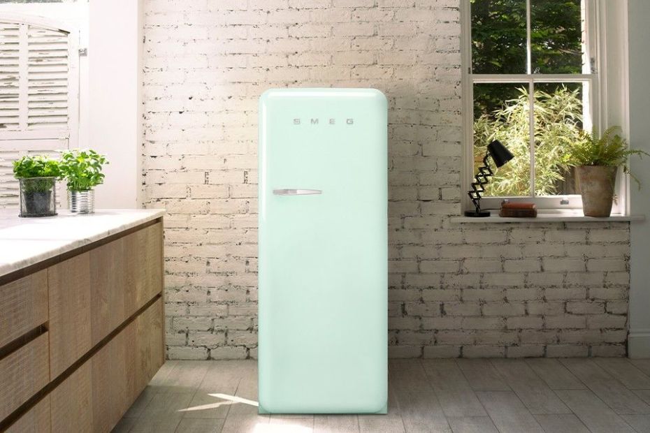 Mintgrüner Smeg FAB-Kühlschrank vor einer weißen Backsteinwand in einer hellen Küche