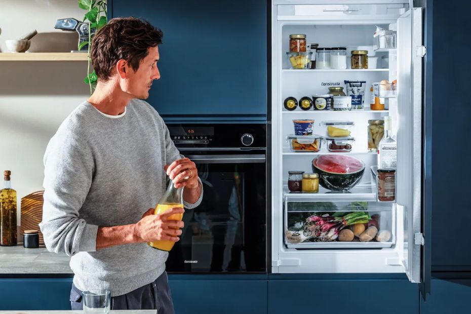 Geöffneter Constructa Kühlschrank neben Constructa Backofen in moderner blauer Küche