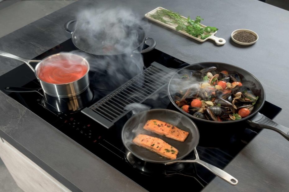 Person mit Smartphone in moderner Küche mit Hoover Einbaugeräten, Backofen und Kühlschrank