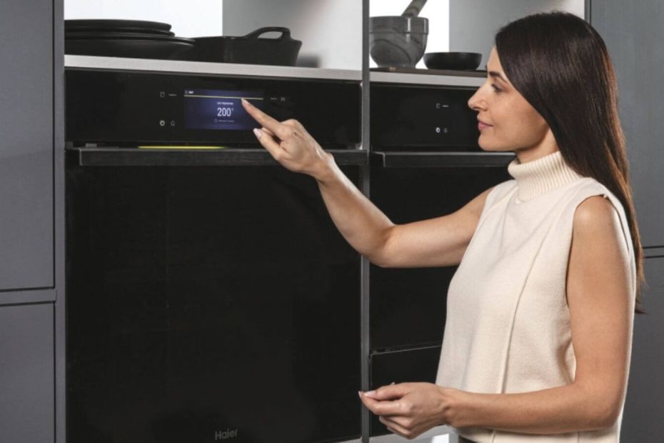 Person bedient Haier Backofen mit Touchdisplay in dunkler Einbauküche