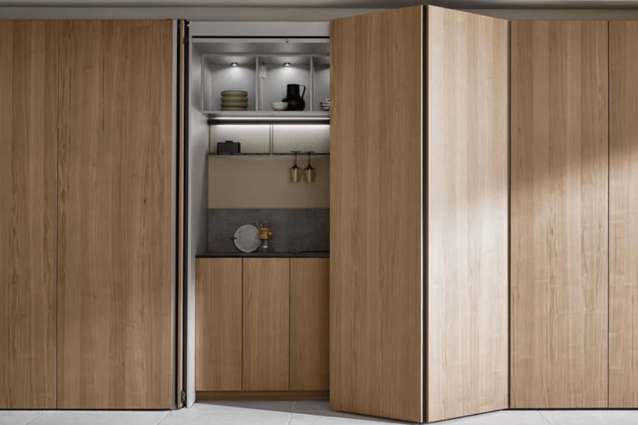 Teilweise geöffnete hohe Türen in Holzoptik geben den Blick auf beleuchtete Regale und eine Arbeitsfläche frei.